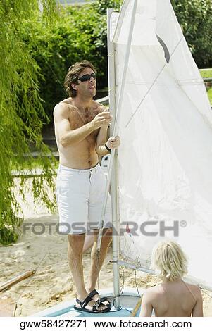 Mid adult man adjusting the sail of a sailboat View Large Photo Image Stock Image - Mid adult man adjusting the sail of a sailboat. Fotosearch