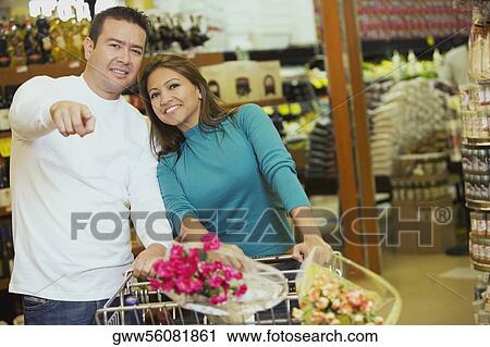 Mid adult man and a young woman standing in a store and smiling View Large Photo Image Stock Image - Mid adult man and a young woman standing in a store and smiling. Fotosearch