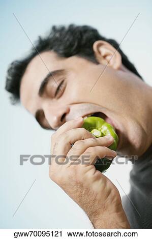 Mid adult man eating a green bell pepper View Large Photo Image Stock Image - Mid adult man eating a green bell pepper. Fotosearch