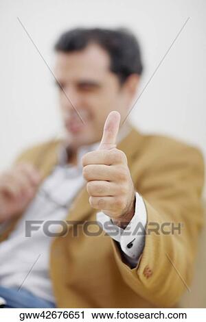 Stock Image - Mid adult man giving a thumbs up sign. Fotosearch