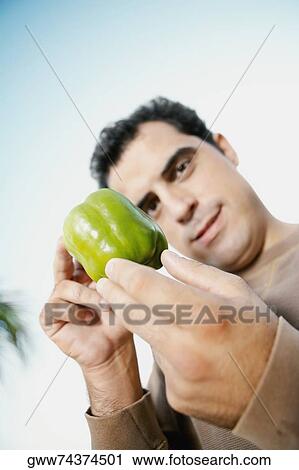 Mid adult man holding a green bell pepper View Large Photo Image Stock Image - Mid adult man holding a green bell pepper. Fotosearch