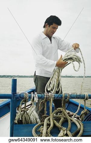 Mid adult man holding a rope and standing in a boat View Large Photo Image Stock Image - Mid adult man holding a rope and standing in a boat. Fotosearch