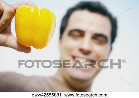 Mid adult man holding a yellow bell pepper View Large Photo Image Stock Image - Mid adult man holding a yellow bell pepper. Fotosearch