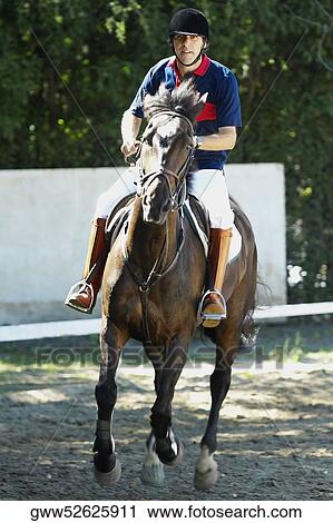 Stock Image - Mid adult man horseback riding. Fotosearch