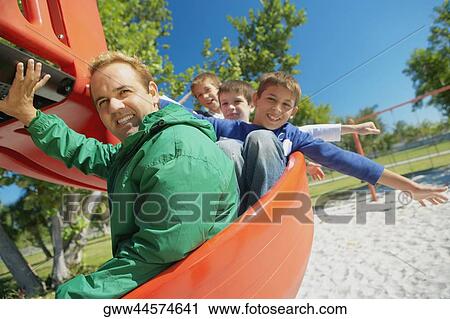 Mid adult man on a slide with three children View Large Photo Image Stock Image - Mid adult man on a slide with three children. Fotosearch