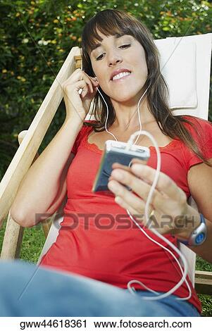 Mid adult woman listening to an mp3 player View Large Photo Image Stock Image - Mid adult woman listening to an mp3 player. Fotosearch