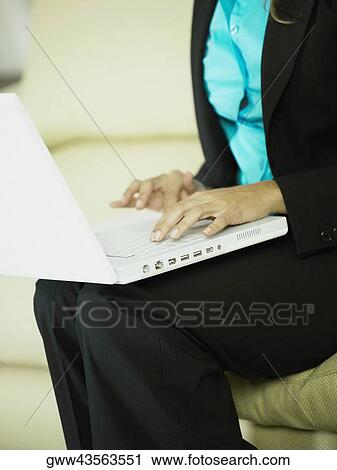 Stock Image - Mid section view of a businesswoman using a laptop. Fotosearch