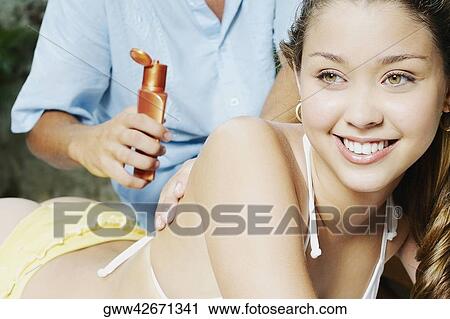Mid section view of a man applying suntan lotion on a young woman's back at the poolside View Large Photo Image Stock Image - Mid section view of a man applying suntan lotion on a young woman's back at the poolside. Fotosearch