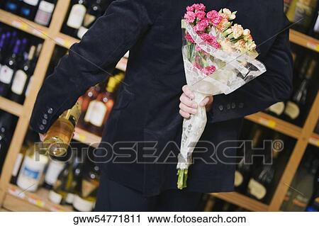 Mid section view of a man holding a bouquet of flowers with a wine bottle View Large Photo Image Stock Image - Mid section view of a man holding a bouquet of flowers with a wine bottle. Fotosearch