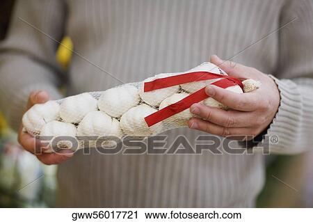 Mid section view of a man holding a packet of garlic View Large Photo Image Stock Image - Mid section view of a man holding a packet of garlic. Fotosearch