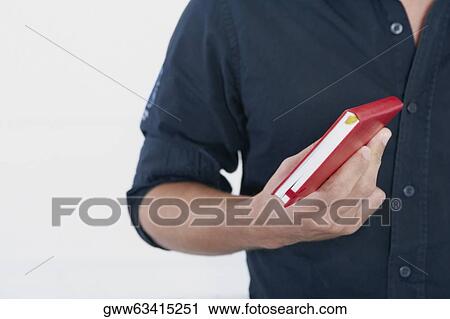 Mid section view of a man holding a diary View Large Photo Image Stock Image - Mid section view of a man holding a diary. Fotosearch