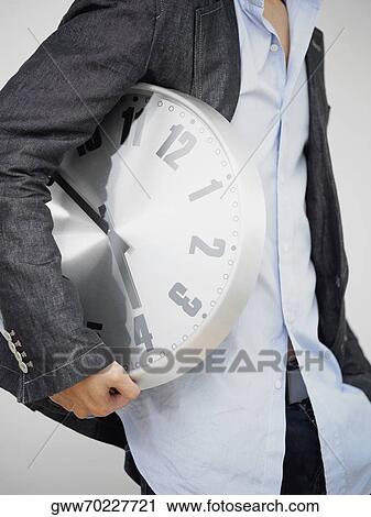 Mid section view of a man holding a clock View Large Photo Image Stock Image - Mid section view of a man holding a clock. Fotosearch