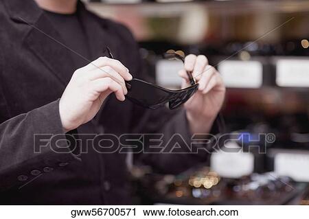 Mid section view of a man holding sunglasses View Large Photo Image Stock Image - Mid section view of a man holding sunglasses. Fotosearch