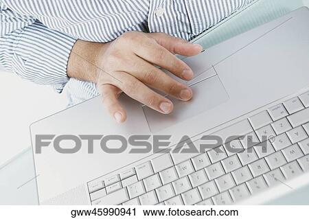 Stock Image - Mid section view of a man working on a laptop. Fotosearch
