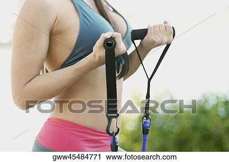 Mid section view of a woman exercising with a resistance band View Large Photo Image Stock Image - Mid section view of a woman exercising with a resistance band. Fotosearch