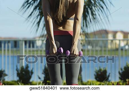 Mid section view of a woman exercising with dumbbells View Large Photo Image Stock Image - Mid section view of a woman exercising with dumbbells. Fotosearch