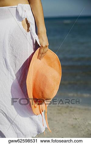Mid section view of a woman holding a hat on the beach View Large Photo Image Stock Image - Mid section view of a woman holding a hat on the beach. Fotosearch
