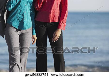 Mid section view of two women standing on the beach View Large Photo Image Stock Image - Mid section view of two women standing on the beach. Fotosearch