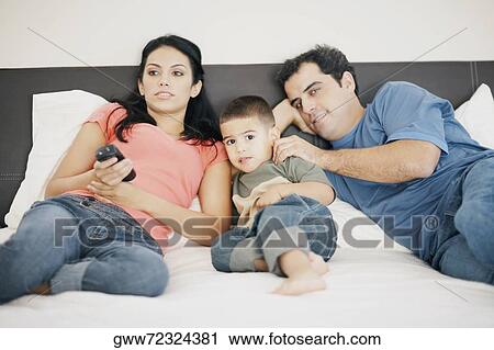 Portrait of a boy lying on the bed with his parents View Large Photo Image Stock Image - Portrait of a boy lying on the bed with his parents. Fotosearch