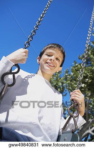 Portrait of a boy sitting on a swing View Large Photo Image Stock Image - Portrait of a boy sitting on a swing. Fotosearch