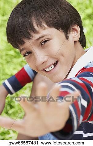 Portrait of a boy smiling and reaching with his hand View Large Photo Image Stock Image - Portrait of a boy smiling and reaching with his hand. Fotosearch