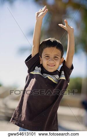 Portrait of a boy standing with his arms raised and smiling View Large Photo Image Stock Image - Portrait of a boy standing with his arms raised and smiling. Fotosearch