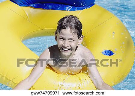 Stock Image - Portrait of a boy with an inflatable ring in a swimming pool. Fotosearch