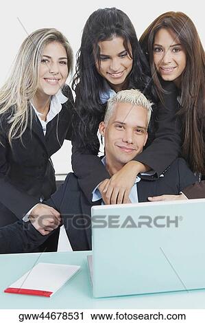 Portrait of a businessman and three businesswomen in front of a laptop View Large Photo Image Stock Image - Portrait of a businessman and three businesswomen in front of a laptop. Fotosearch