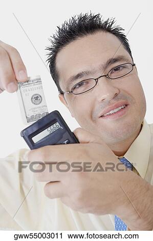 Portrait of a businessman holding a calculator and a dollar bill View Large Photo Image Stock Image - Portrait of a businessman holding a calculator and a dollar bill. Fotosearch
