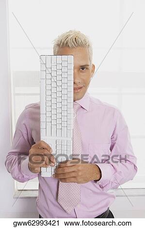 Portrait of a businessman holding a computer keyboard in front of his face View Large Photo Image Stock Image - Portrait of a businessman holding a computer keyboard in front of his face. Fotosearch