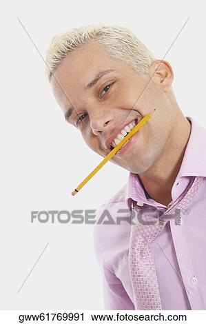 Stock Image - Portrait of a businessman smiling and holding a pencil between his teeth. Fotosearch
