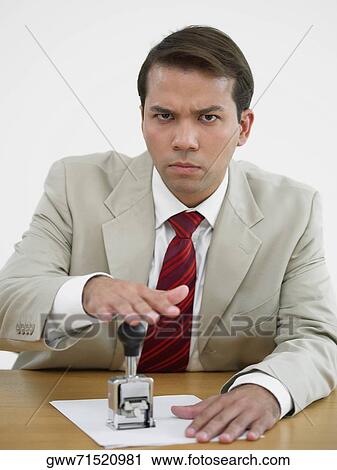 Portrait of a businessman stamping on a sheet of paper View Large Photo Image Stock Image - Portrait of a businessman stamping on a sheet of paper. Fotosearch