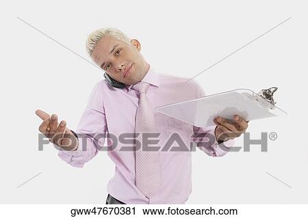 Portrait of a businessman talking on a mobile phone and holding a clipboard View Large Photo Image Stock Image - Portrait of a businessman talking on a mobile phone and holding a clipboard. Fotosearch