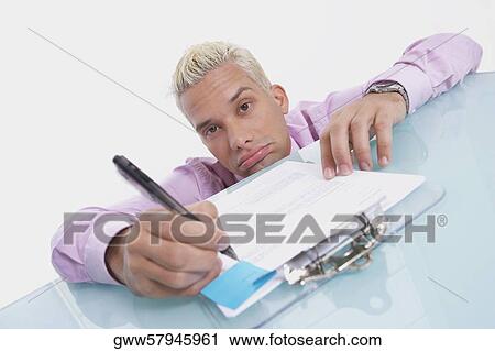 Portrait of a businessman writing on a sheet of paper and looking sad View Large Photo Image Stock Image - Portrait of a businessman writing on a sheet of paper and looking sad. Fotosearch
