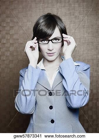 Stock Image - Portrait of a businesswoman adjusting her eyeglasses. Fotosearch