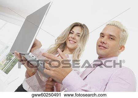 Portrait of a businesswoman and a businessman using a laptop and smiling View Large Photo Image Stock Image - Portrait of a businesswoman and a businessman using a laptop and smiling. Fotosearch