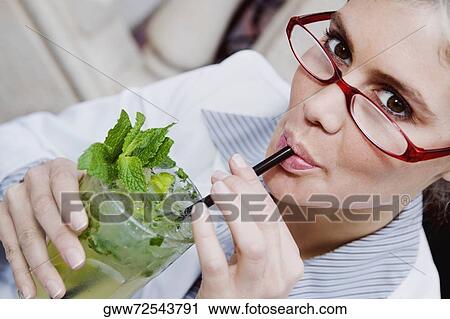 Stock Image - Portrait of a businesswoman drinking a glass of mint julep. Fotosearch