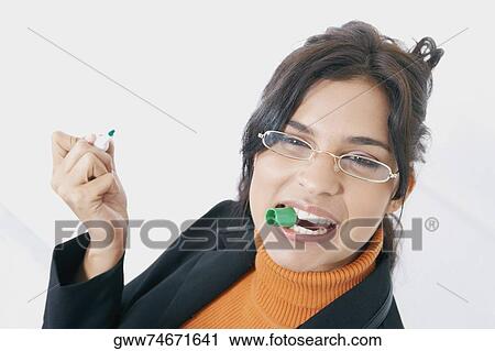 Portrait of a businesswoman holding lid of a pen in her mouth View Large Photo Image Stock Image - Portrait of a businesswoman holding lid of a pen in her mouth. Fotosearch