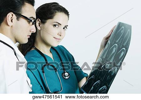 Portrait of a female doctor holding an X-Ray with a male doctor beside her View Large Photo Image Stock Image - Portrait of a female doctor holding an X-Ray with a male doctor beside her. Fotosearch
