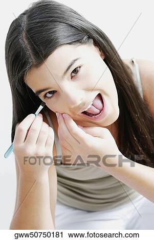 Stock Image - Portrait of a girl applying eyeshadow on her eyes. Fotosearch