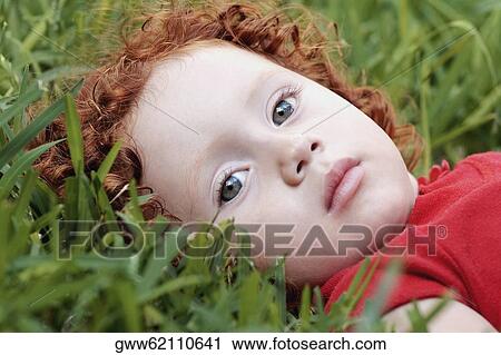 Stock Image - Portrait of a girl laying on the grass. Fotosearch