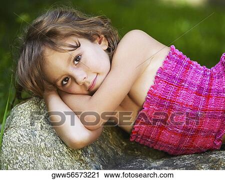 Stock Image - Portrait of a girl lying on a rock. Fotosearch