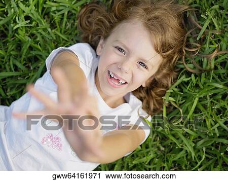 Portrait of a girl lying on the grass and smiling View Large Photo Image Stock Image - Portrait of a girl lying on the grass and smiling. Fotosearch