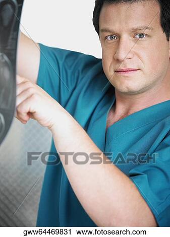Stock Image - Portrait of a male doctor examining an X-Ray. Fotosearch