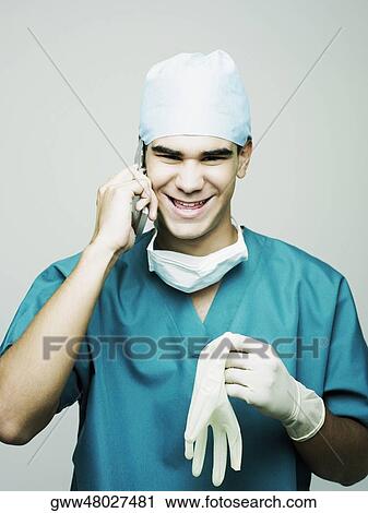 Portrait of a male surgeon smiling and using a mobile phone View Large Photo Image Stock Image - Portrait of a male surgeon smiling and using a mobile phone. Fotosearch