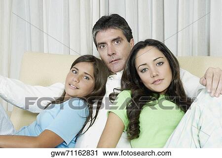 Portrait of a mature man sitting with his two daughters on a couch View Large Photo Image Stock Image - Portrait of a mature man sitting with his two daughters on a couch. Fotosearch