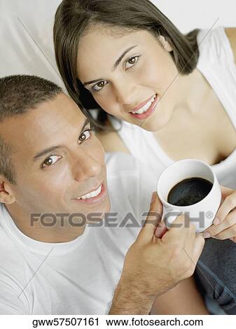 Portrait of a mid adult man and a young woman holding a cup of black tea and smiling View Large Photo Image Stock Image - Portrait of a mid adult man and a young woman holding a cup of black tea and smiling. Fotosearch