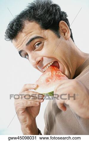 Portrait of a mid adult man eating a slice of watermelon View Large Photo Image Stock Image - Portrait of a mid adult man eating a slice of watermelon. Fotosearch