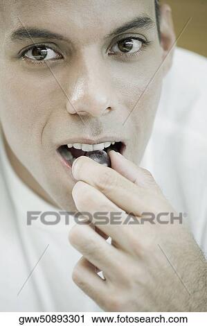 Portrait of a mid adult man eating a red grape View Large Photo Image Stock Image - Portrait of a mid adult man eating a red grape. Fotosearch