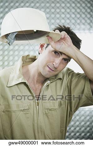 Portrait of a mid adult man holding a hardhat and wiping his forehead View Large Photo Image Stock Image - Portrait of a mid adult man holding a hardhat and wiping his forehead. Fotosearch